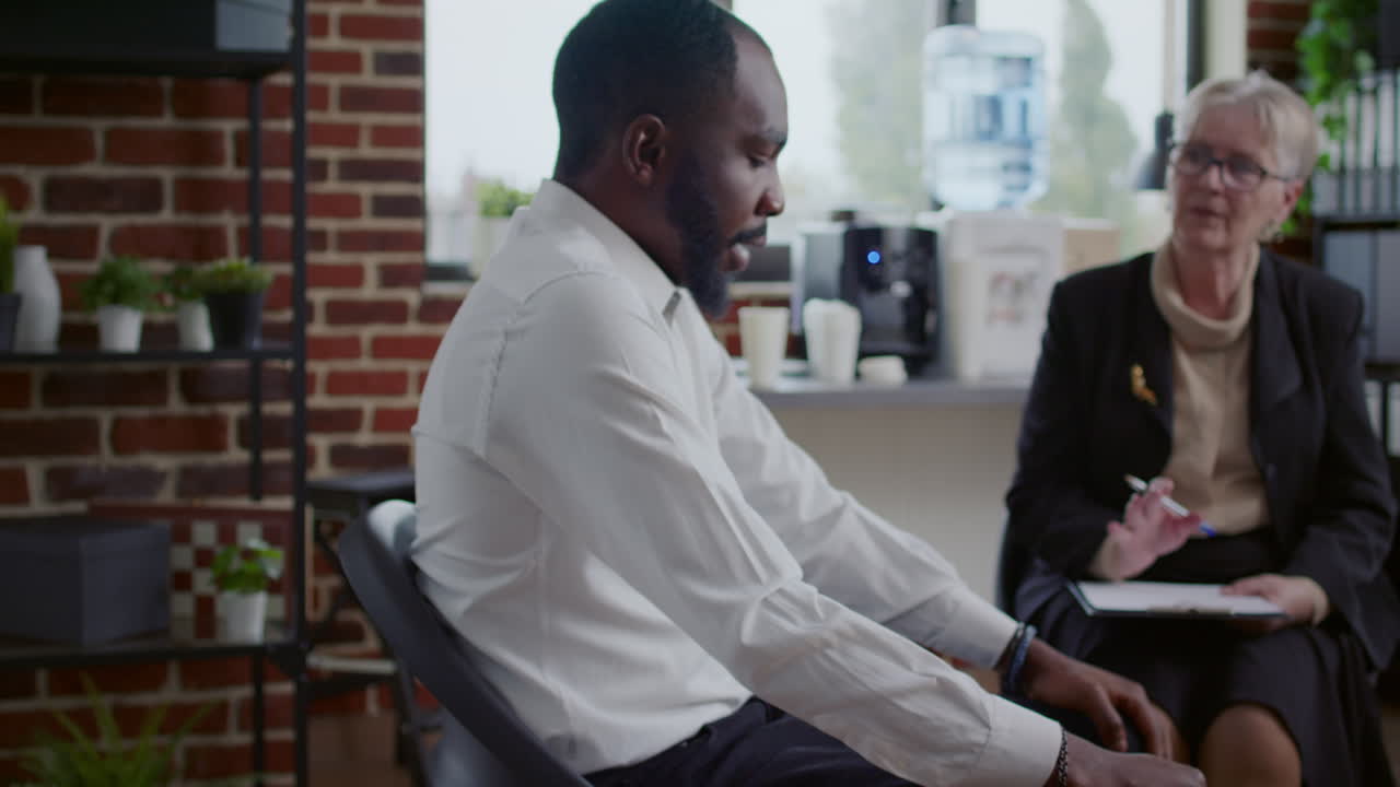 African american man talking about alcohol addiction at aa therapy meeting with people