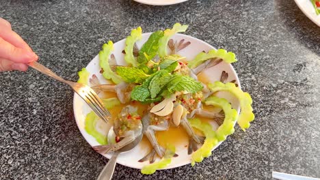 hands arranging shrimp dish with herbs and sauce