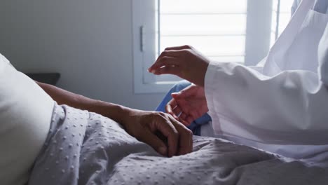 close up of senior mixed race man with female doctor home visiting holding hands