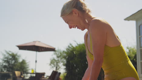 grandparents having fun with granddaughter swimming in pool on family summer holiday