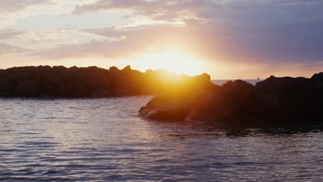 sunset over the ocean with rocks