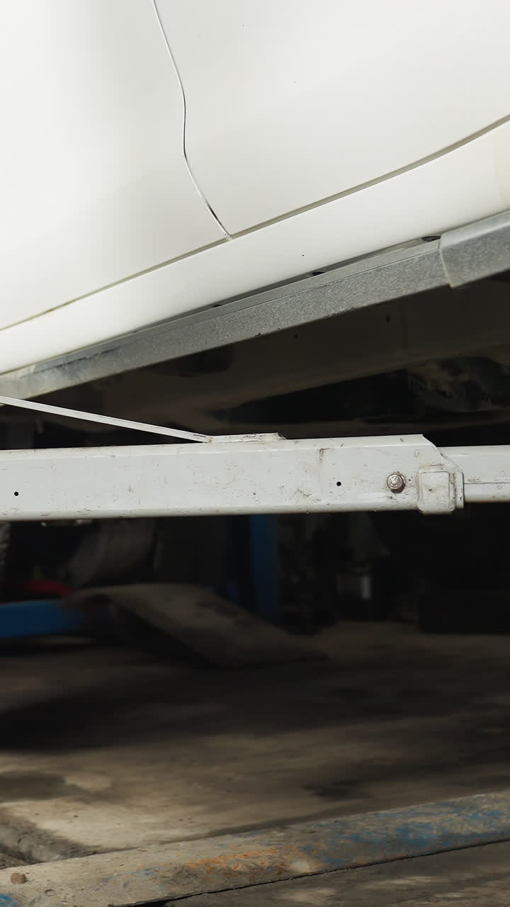 차고에서 자동차 하이드라릭 엘리베이터에 의해 천천히 들어올려지는 색 자동차, 파란색 산업용 자동차 엘리베이트 구조에 의해 지원, 차체와 타이어가 보이고, 기계적 프로세스를 보여줍니다.