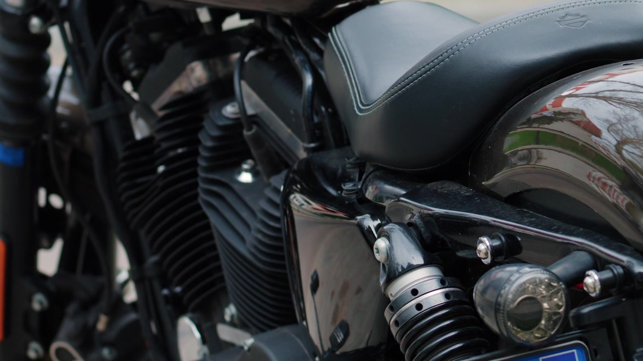 Primo piano di un motore di moto nero, sospensione posteriore e dettagli lucidi della carrozzeria