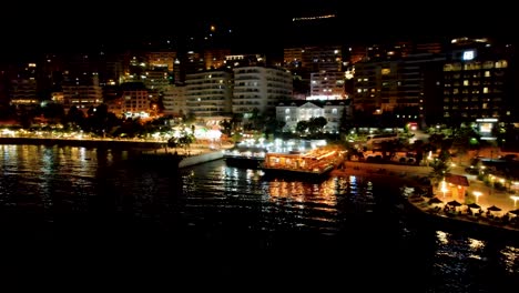 night magic at saranda: anchored ships, illuminated pier lights, and a bustling promenade paint a stunning picture of coastal tourism