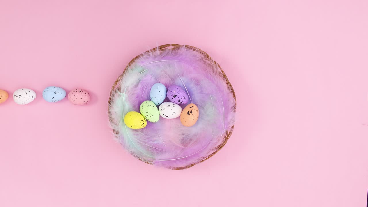 Easter eggs come in wooden basket with feathers on pastel pink theme. Stop motion