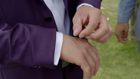 el novio ajusta los puños de su chaqueta y los botones decorativos de su camisa