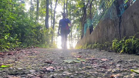 tiro de ángulo bajo del fotógrafo independiente caminando en el camino del bosque