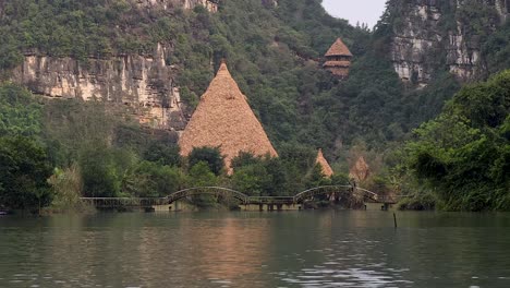 river, huts, and bridge in lush landscape