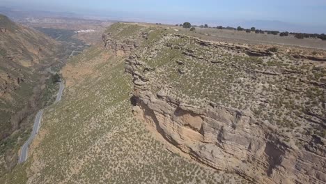 Aerial-view-of-a-badlands-desert-ravine-area-with-a-dirt-road-and-car-driving-on-it