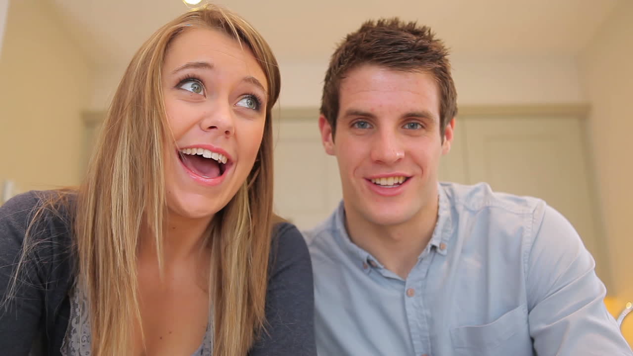 um casal a acenar e a falar num vídeo chat.