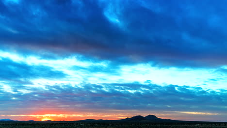 the sun sets with brilliant colors in the cloudscape in this desert time lapse - wide angle static