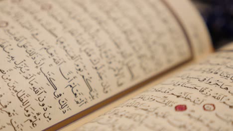 side shot of an opened quran, the focus moves along the opened page while the camera moves