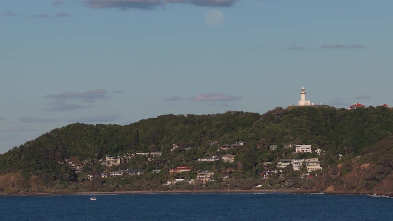 Farol de Cape Byron com o bairro na encosta da Praia de Wategos em Byron Bay, Nova Gales do Sul, Austrália. Vista aérea.