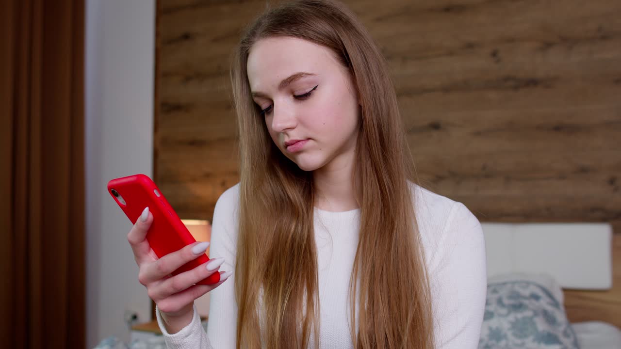 소녀는 스마트폰 화면을 보고 성공적으로 온라인 주문을 하고, 천천히 탐색하고, 온라인에서 서핑합니다.