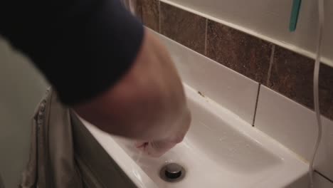 a person with a wristwatch squeezing earneslty in a small sink