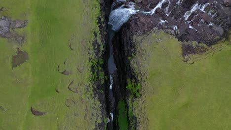 Waterfall-ravine-gorge-in-Faroe-Islands-countryside,-aerial-birds-eye-view