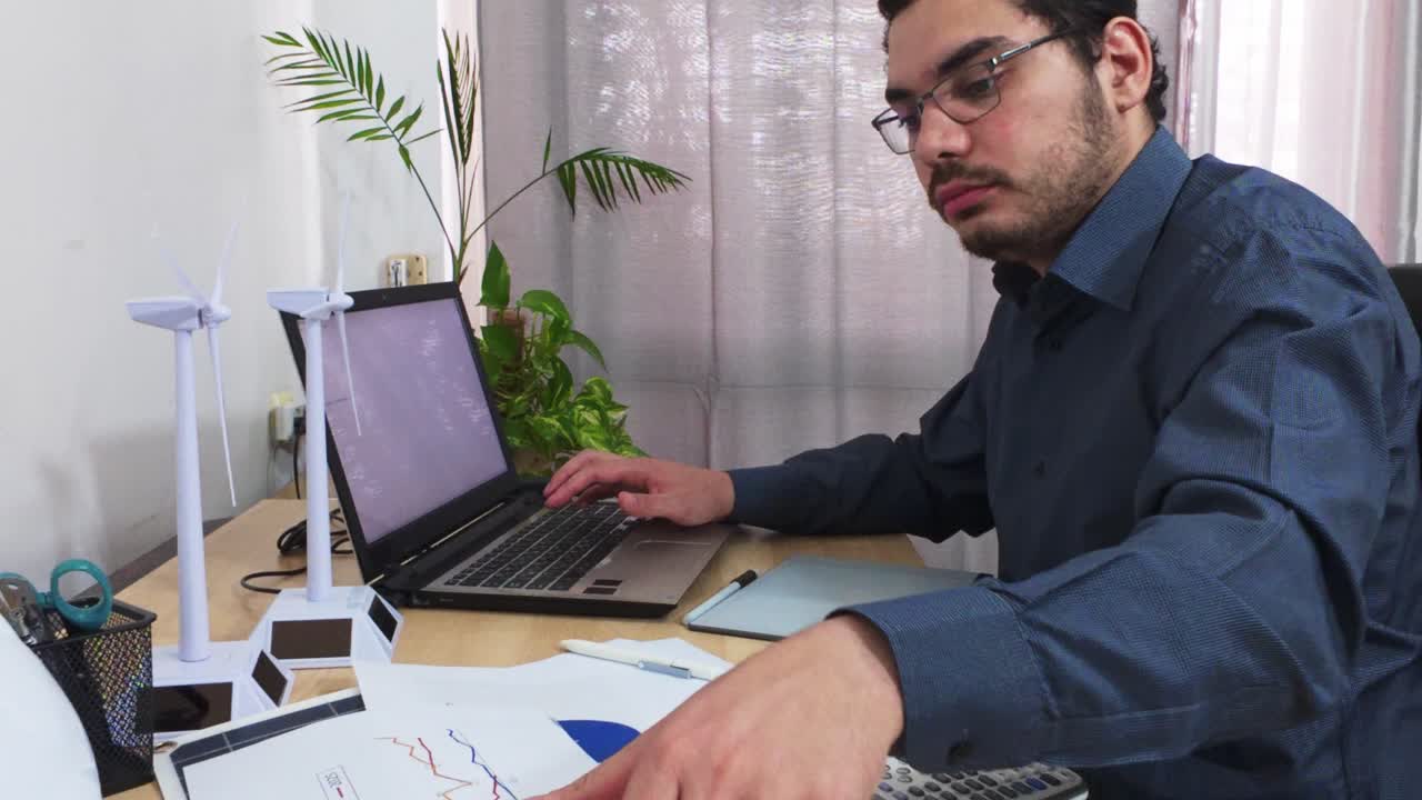 Engineer Reviewing Documents While Working on a Laptop