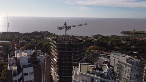 aerial view of crane on top of building roof under construction and sea in background, buenos aires in argentina