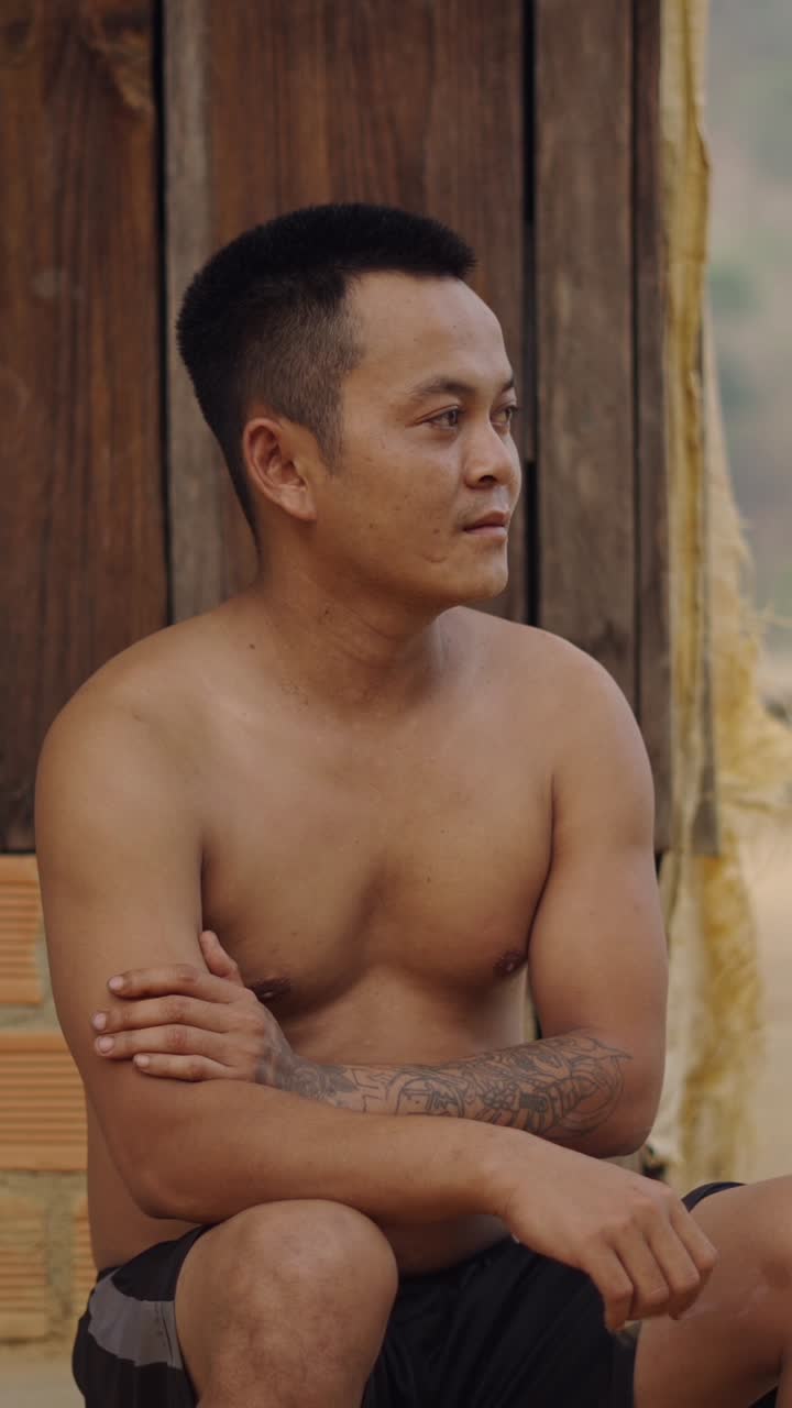 Shirtless man with tattoo sitting outdoors