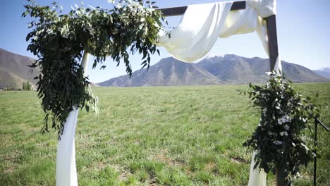 wedding arch with white cloth and flowers for an outdoor wedding ceremony in the meadow - wide shot