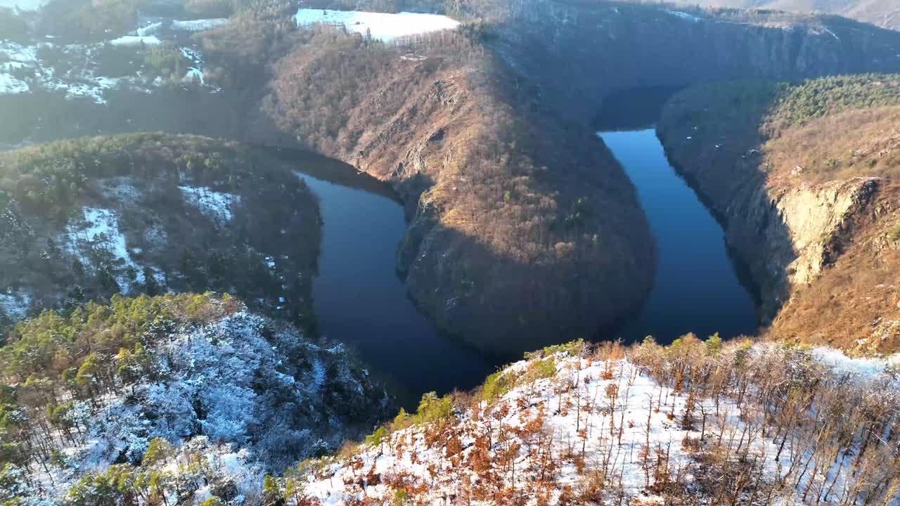 Rolling Mountains Towering Above a Horse shoe River in Mountains - aerial pan down shot