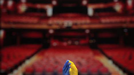 Blaue-Und-Gelbe-Kleine-Fingerhand-Fingerpuppenspielzeuge-Klatschen-Vor-Verschwommenem-Theaterhintergrund