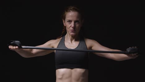 studio shot of mature woman wearing gym fitness clothing exercising with resistance band