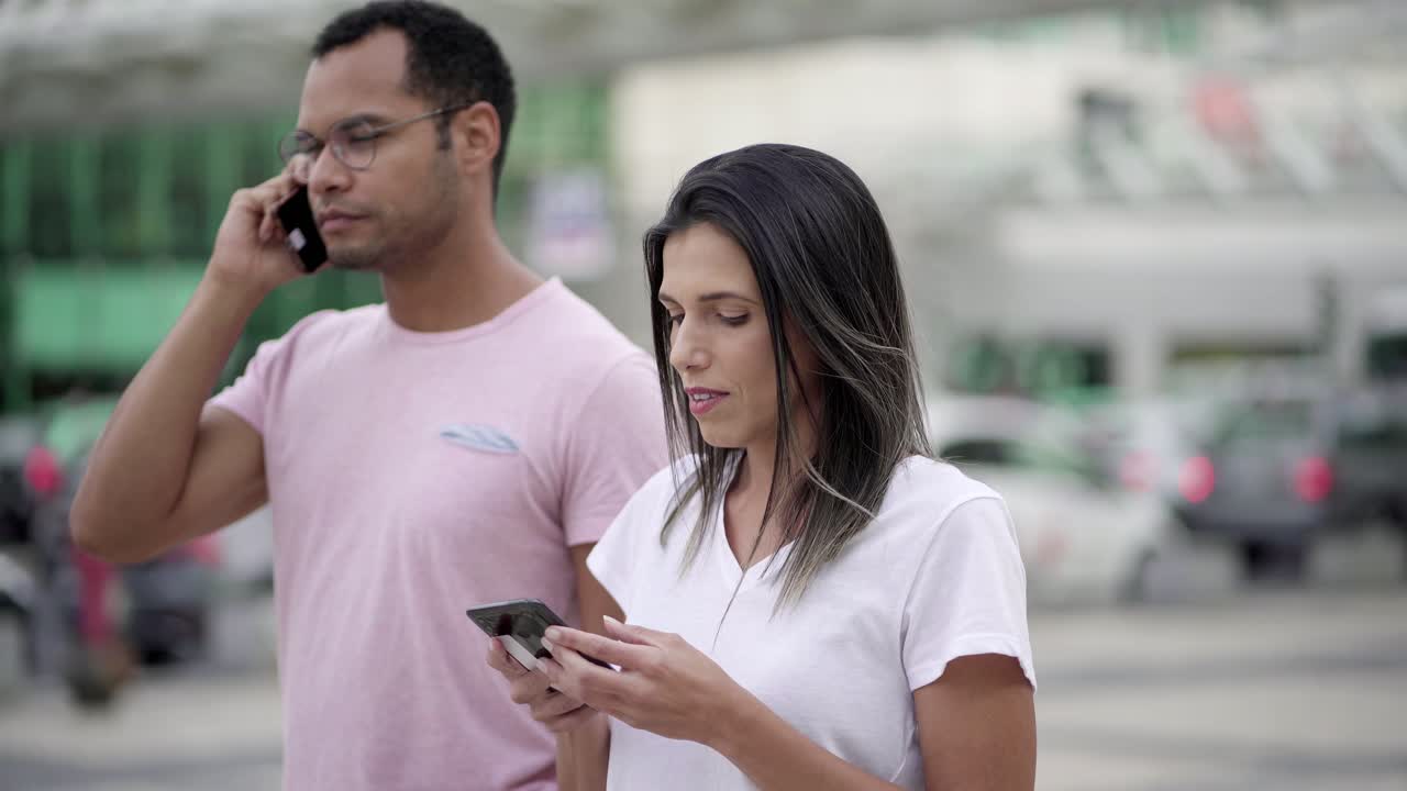 jóvenes alegres caminando por la calle con teléfonos inteligentes
