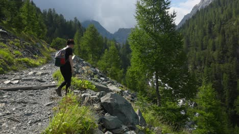 female hiker walking through rocky mountain trails near lago lagazzuolo in valmalenco, north of italy