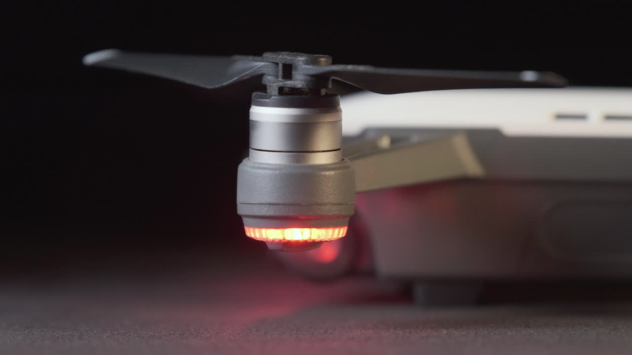 드론 불빛이 박이는 색 dji 스파크 드론의 왼쪽 측면과 프로펠러를 가로질러 트랙