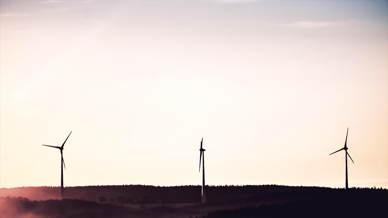 숲 위에서 해가 뜨고 해가 지는 풍력 터빈