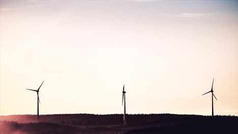 wind turbines at sunrise/sunset over a forest