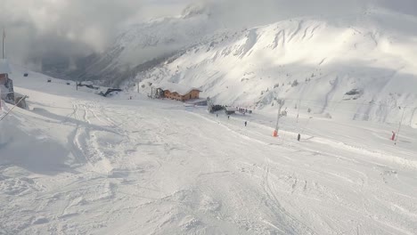 Still-shot-looking-down-slope-at-ski-lift-and-skiers-descending-mountain-on-sunny-day