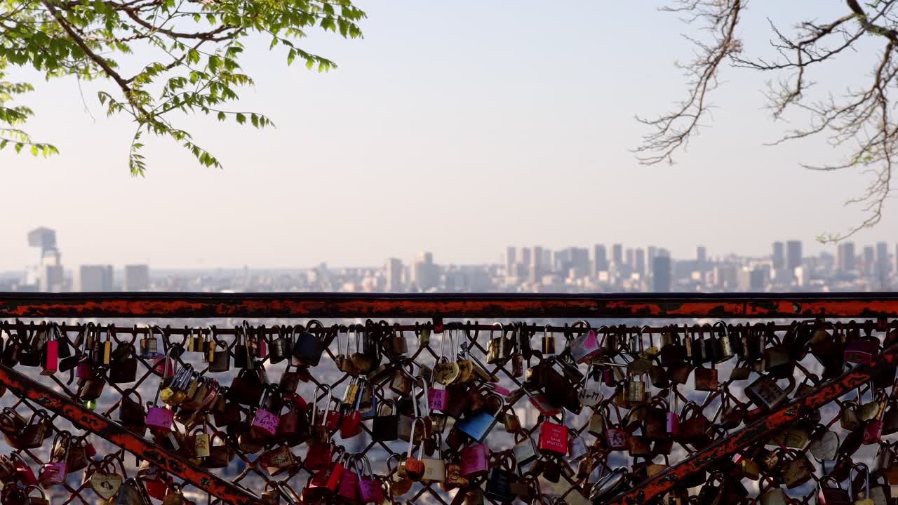 Wide angle view of Love locks in a fence and Paris skyline in the background from Montmartre during summer daylight.