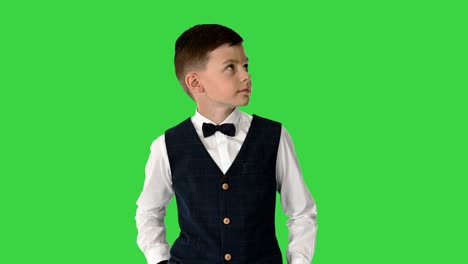 schoolboy in waistcoat and bow tie checking his watch, rolling eyes and sighing on a green screen, chroma key