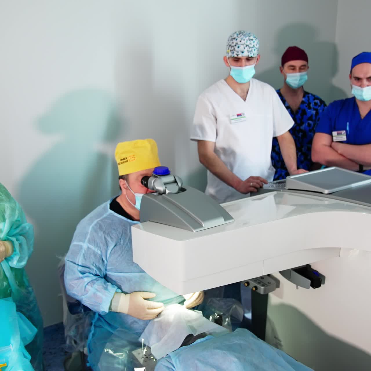 Equipo profesional trabajando en una operación de corrección ocular. Paciente preparado para la operación bajo el microscopio. Vista de ángulo alto.