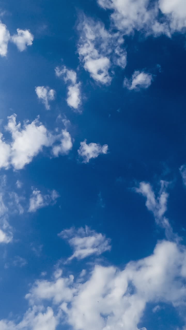 Light white clouds spreading along the blue skies. Beautiful cotton clouds looking heavenly in the sun rays. Timelapse. Vertical video