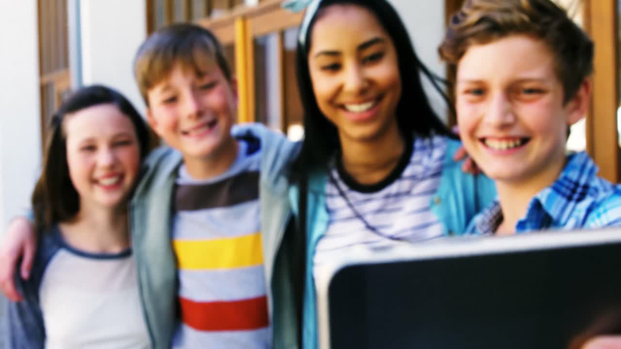 웃는 학생 들 이  ⁇ 드폰 으로 셀카 를 찍고 있다