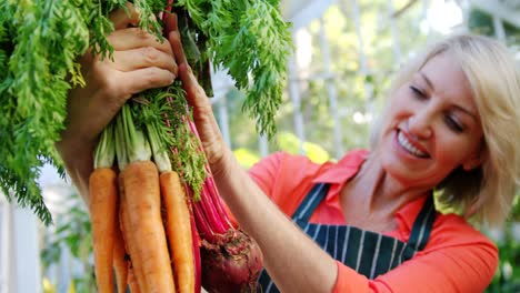 mujer madura sosteniendo un ramo de verduras
