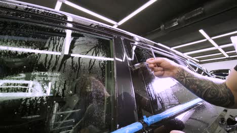 hombre que cubre el coche con cinta de poliuretano de vinilo. películas para el coche. pegatina película protectora en el coche