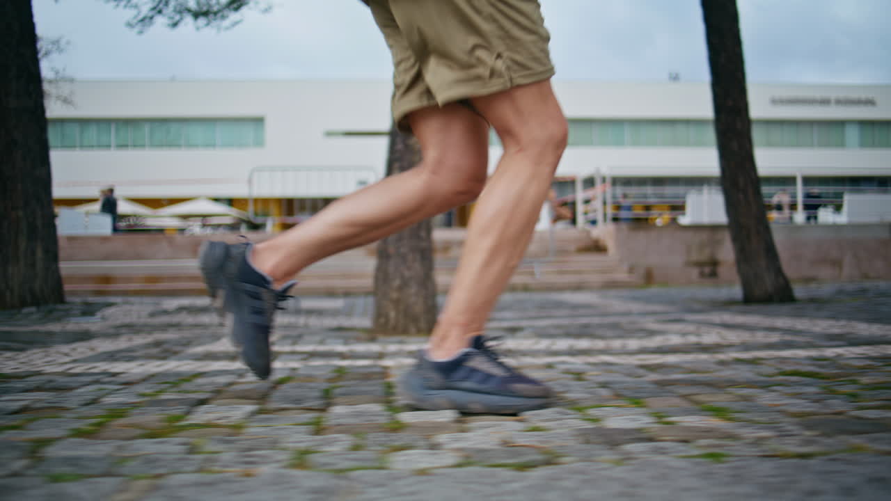 Sportsman sneakers running outdoors closeup. Fit guy training in city park