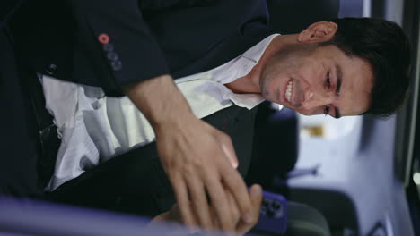 man in a suit looking at his smartphone in a car