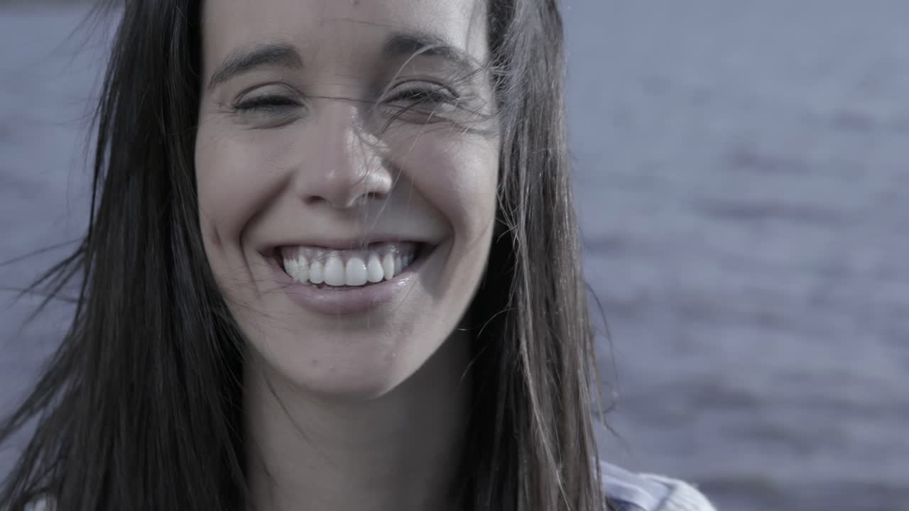 Primer plano de una joven feliz sonriendo y riendo junto al agua