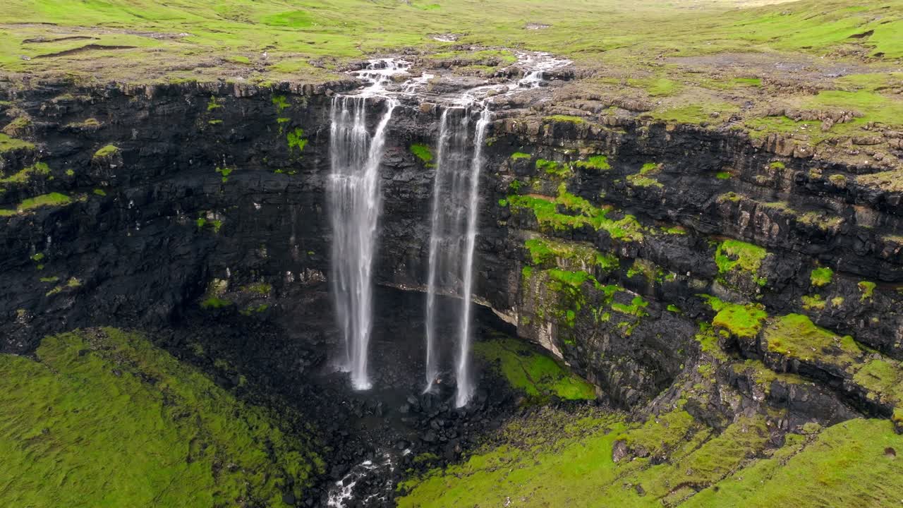 una impresionante vista aérea de dos cascadas que caen en cascada por acantilados rocosos en las islas feroe