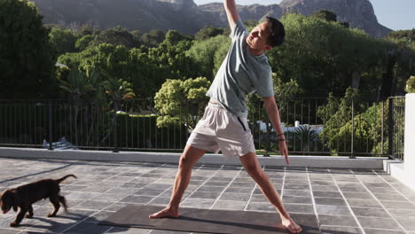 asian man practicing yoga on balcony with scenic mountain view