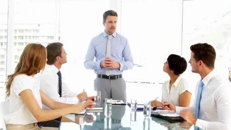 Businessman-standing-and-speaking-during-meeting