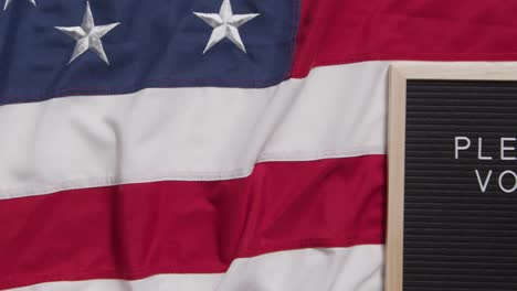 Schild-Mit-Der-Aufschrift-„Bitte-Stimmen-Sie-Ab“-Liegt-Auf-Der-US-Flagge-„Stars-And-Stripes“-Für-Die-Amerikanische-Wahl-2024-1