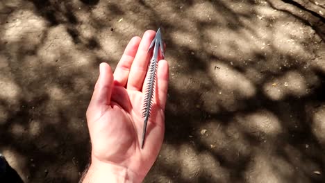 A-single-hand-holding-and-moving-a-hand-crafted-arrowhead-in-Tanzania,-Africa