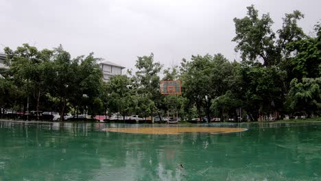 la lluvia cae en el suelo de la cancha de baloncesto al aire libre en el parque.
