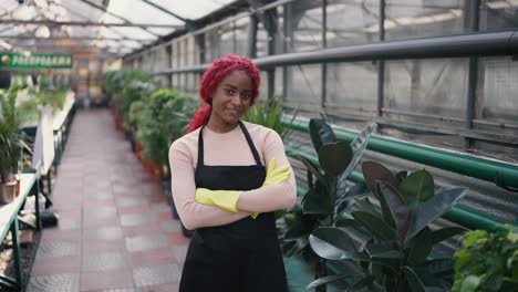 portrait of young multiethnic woman looking to camera, posing while standing in greenhouse